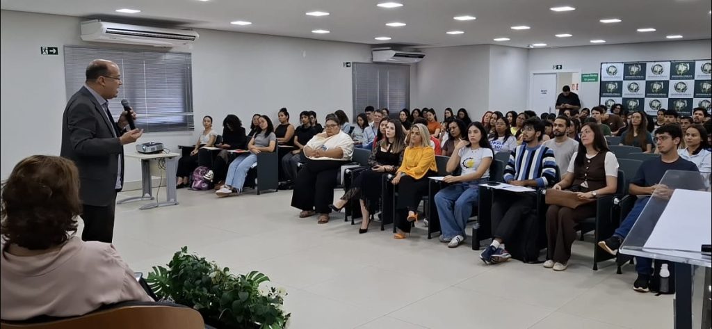 Vice-governador Barbosinha, usando terno, de pé e com microfone na mão, fala a estudantes do MS Supera.
 